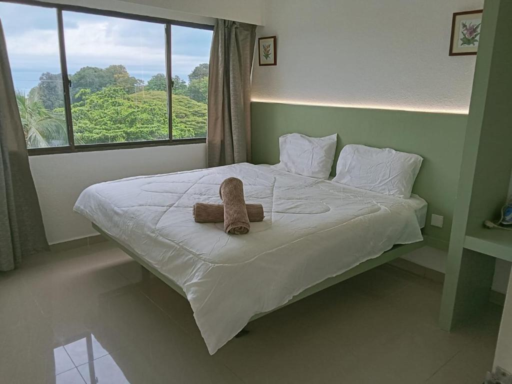 Un osito de peluche sentado en una cama en un dormitorio. en Sri Sayang Home Stay, en George Town