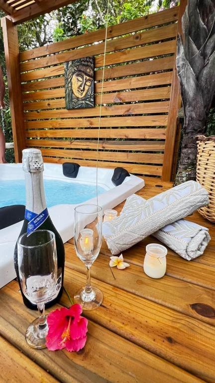 a bottle of wine and glasses on a wooden table at Pousada Aurora in Praia do Rosa