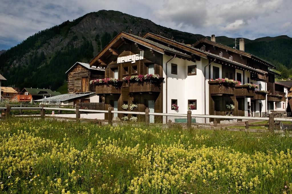 a building with flowers in front of a mountain at Residence Nevegall in Livigno