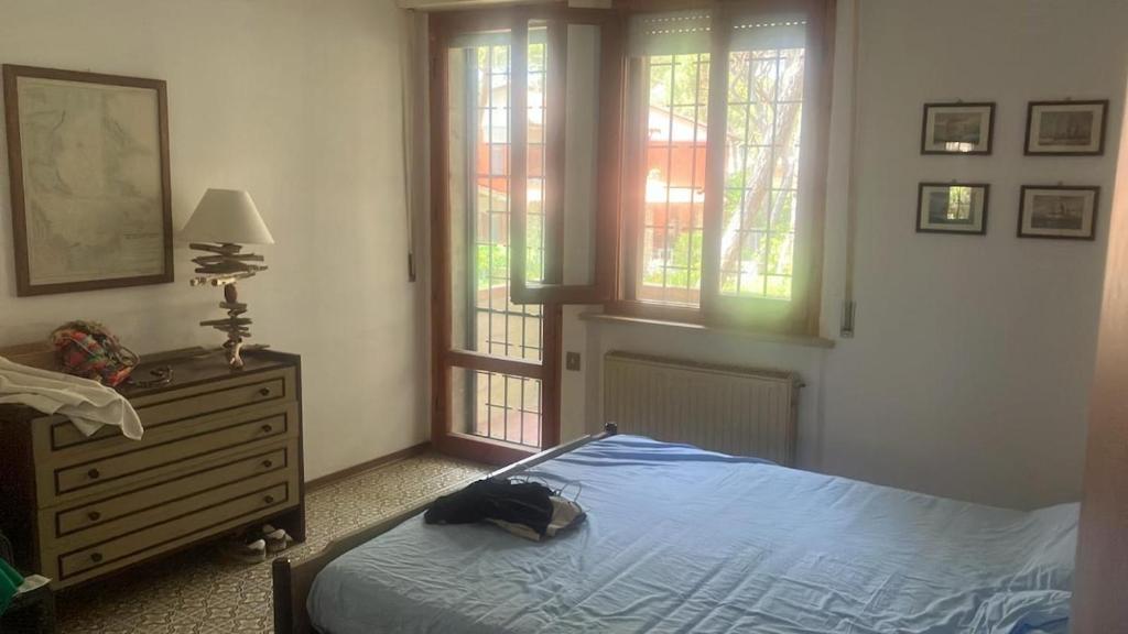 a bedroom with a bed and a dresser and windows at At Franca's house between Pineta&Mare Wi-Fi in Grosseto