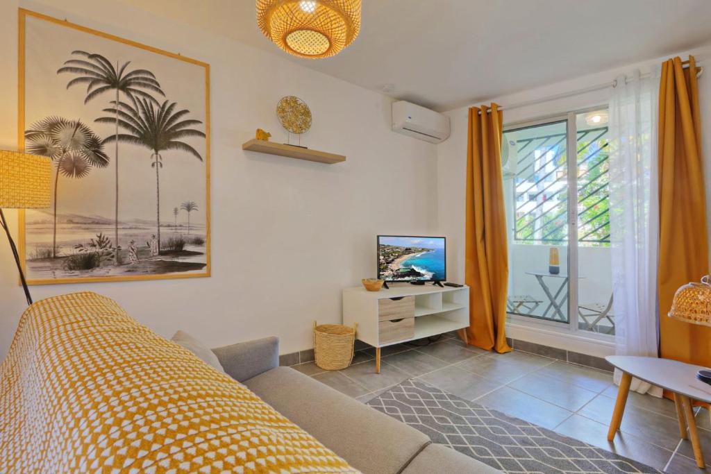 a living room with a bed and a tv and a window at Le Studio Tanzantan in Saint-Paul