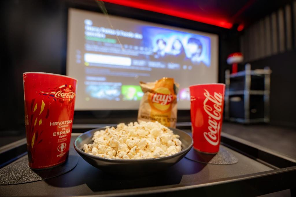 a counter with a bowl of popcorn and two soda cups at INFINITY I Seventharts I Cinema room in Angoulême