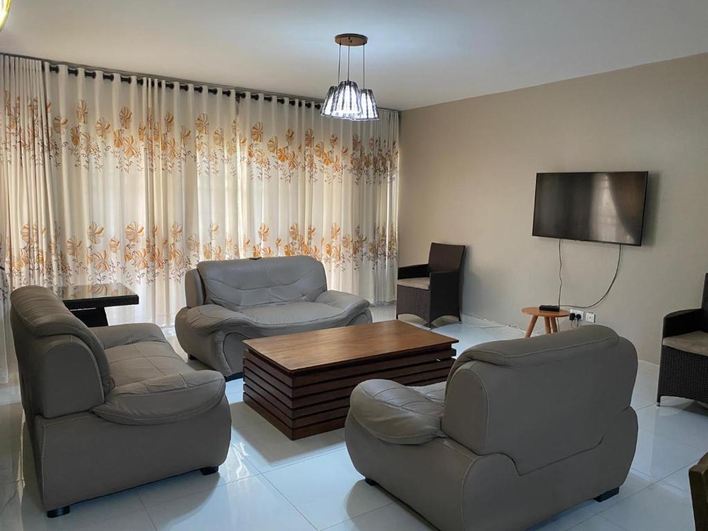 Una sala de estar con dos sillas y un televisor. en Green top Green top Cordier apartments, en Kampala