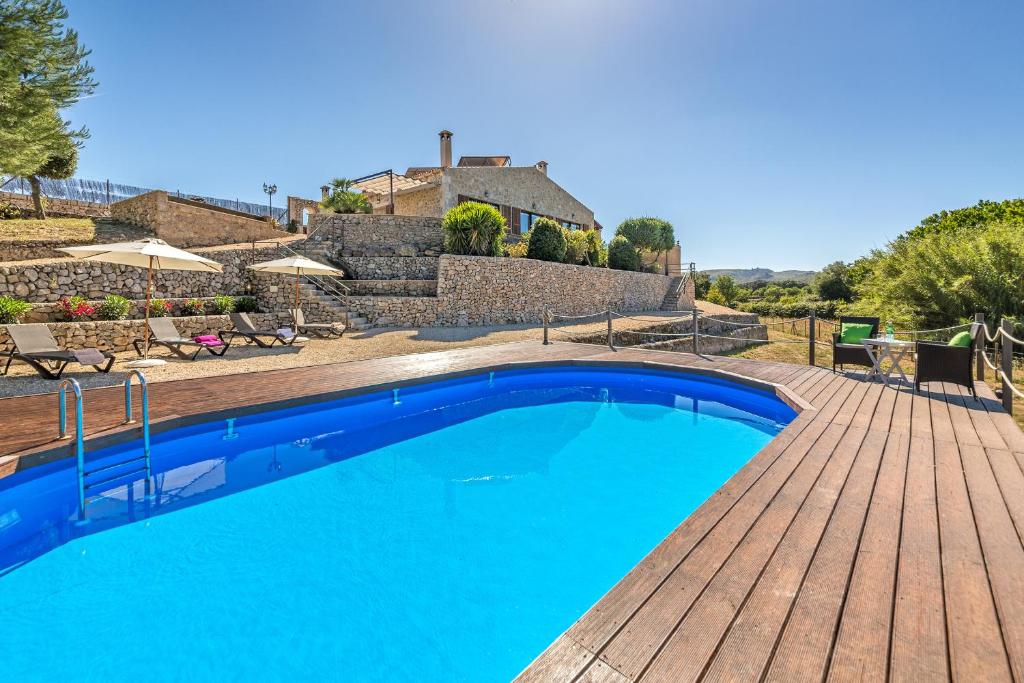una piscina azul con terraza de madera en Finca Wellnatura, en Artà