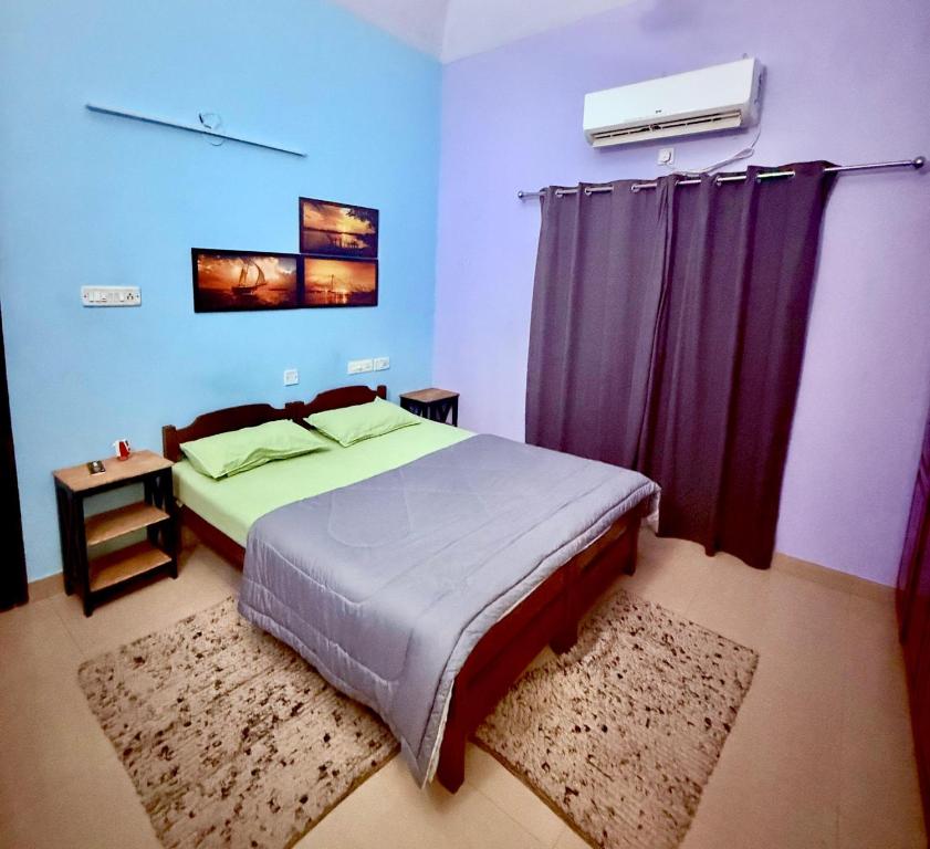 1 dormitorio con 1 cama grande y cortinas moradas en Vedic Villa, en Alleppey