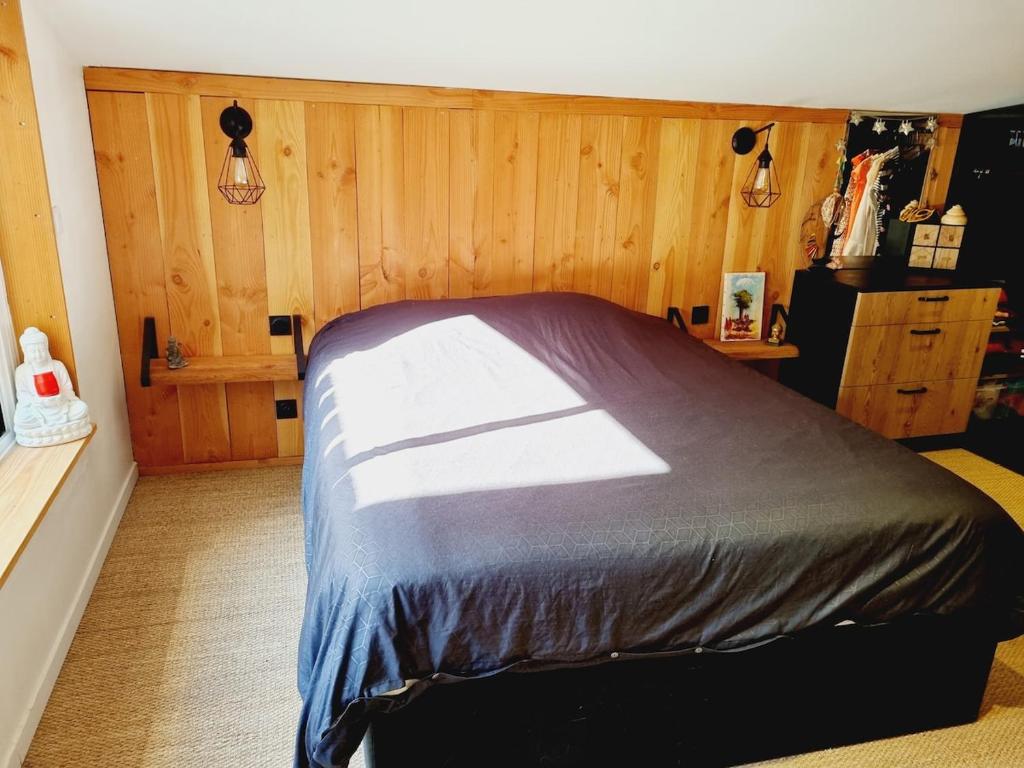 a bedroom with a bed with a wooden wall at Maison avec jardin proche des bords de Loire in Les Ponts-de-Cé