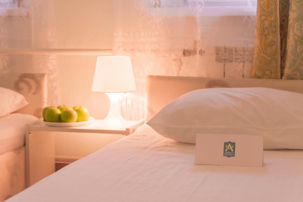 a bed with a white pillow and a plate of apples at Andron Hotel on Ilyicha Square in Moscow