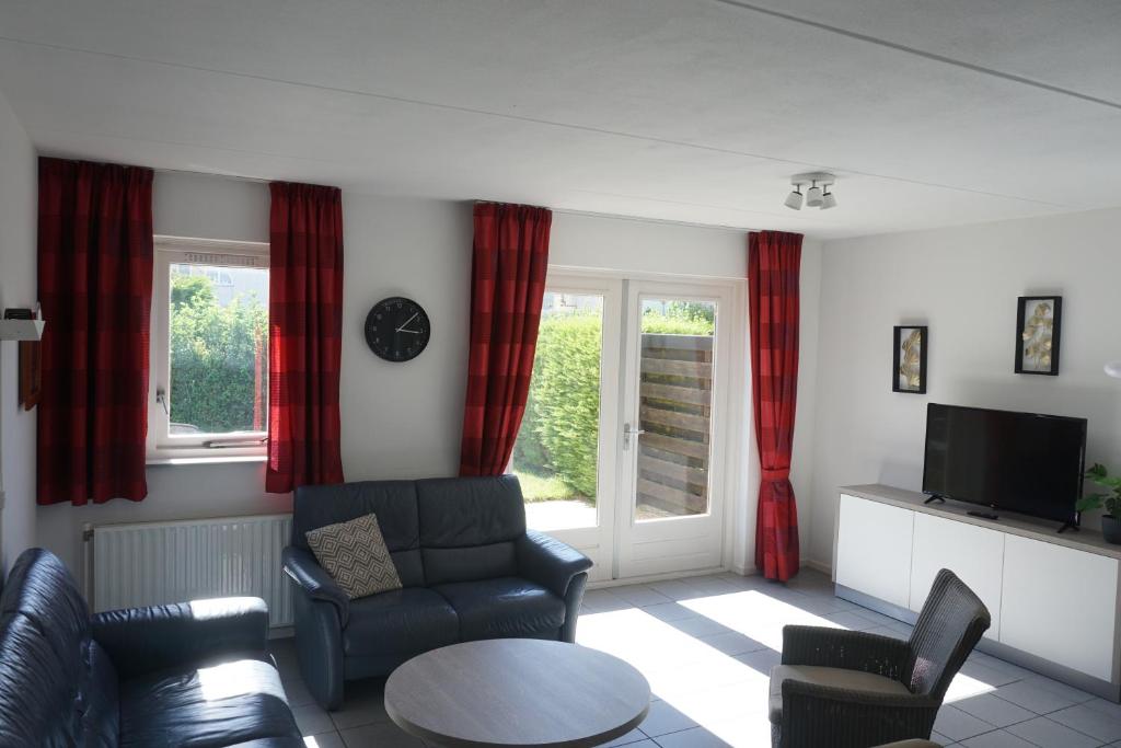 a living room with red curtains and a couch and a table at Kustverhuur, Vakantiepark Fort Soleil 26 in Breskens