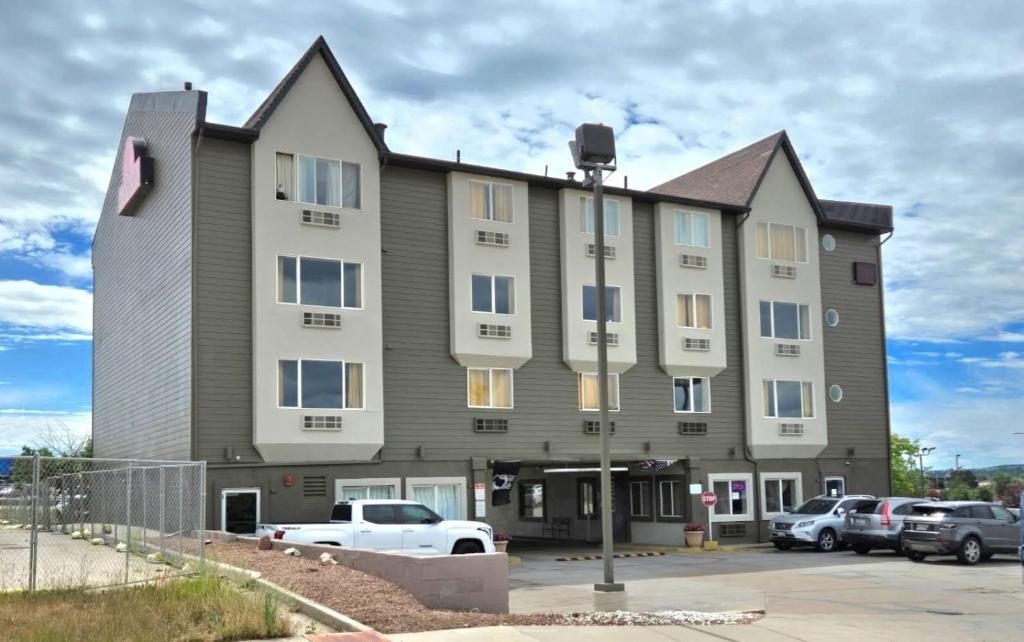 a large building with cars parked in a parking lot at Olympia Inn in Colorado Springs