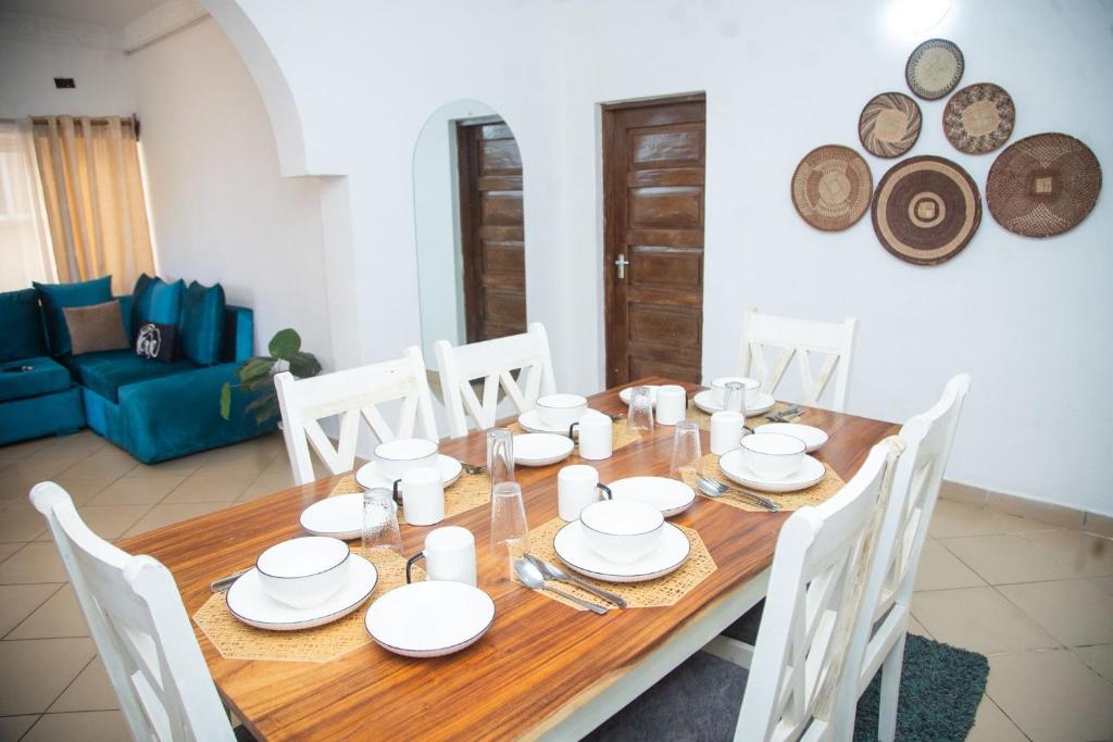 Una mesa de comedor de madera con platos blancos encima. en Ndoto House, en Ukunda