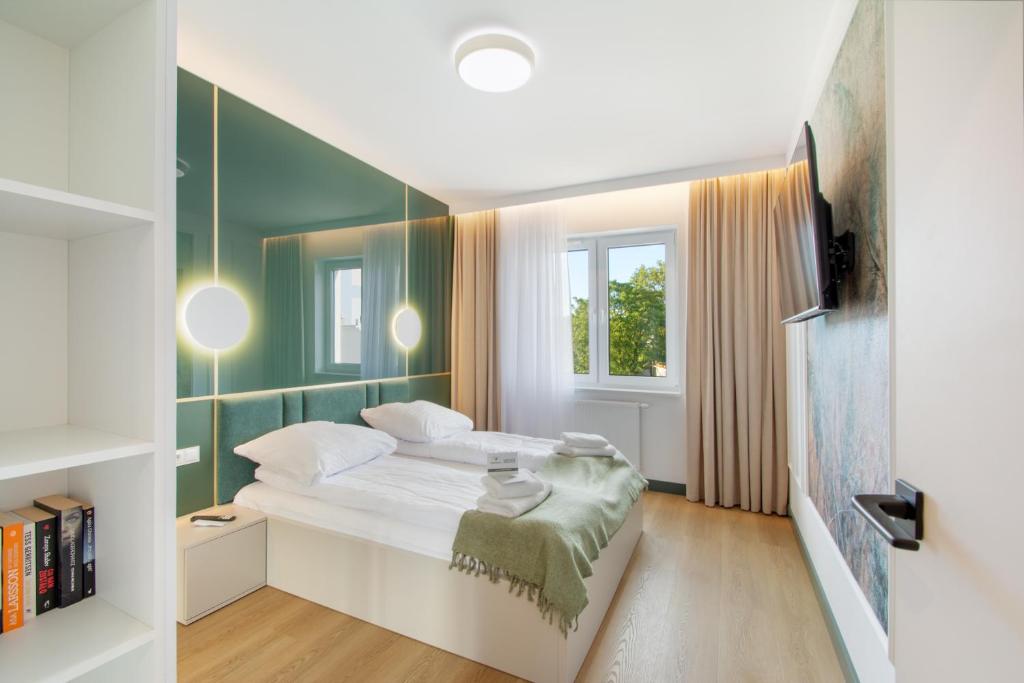 ein Schlafzimmer mit einem Bett und einer grünen Wand in der Unterkunft NORTH Apartments, Vibe Ustka in Ustka