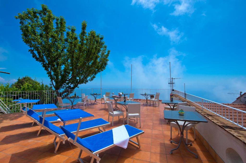 a patio with tables and chairs and a view of the ocean at L'Incanto in Furore