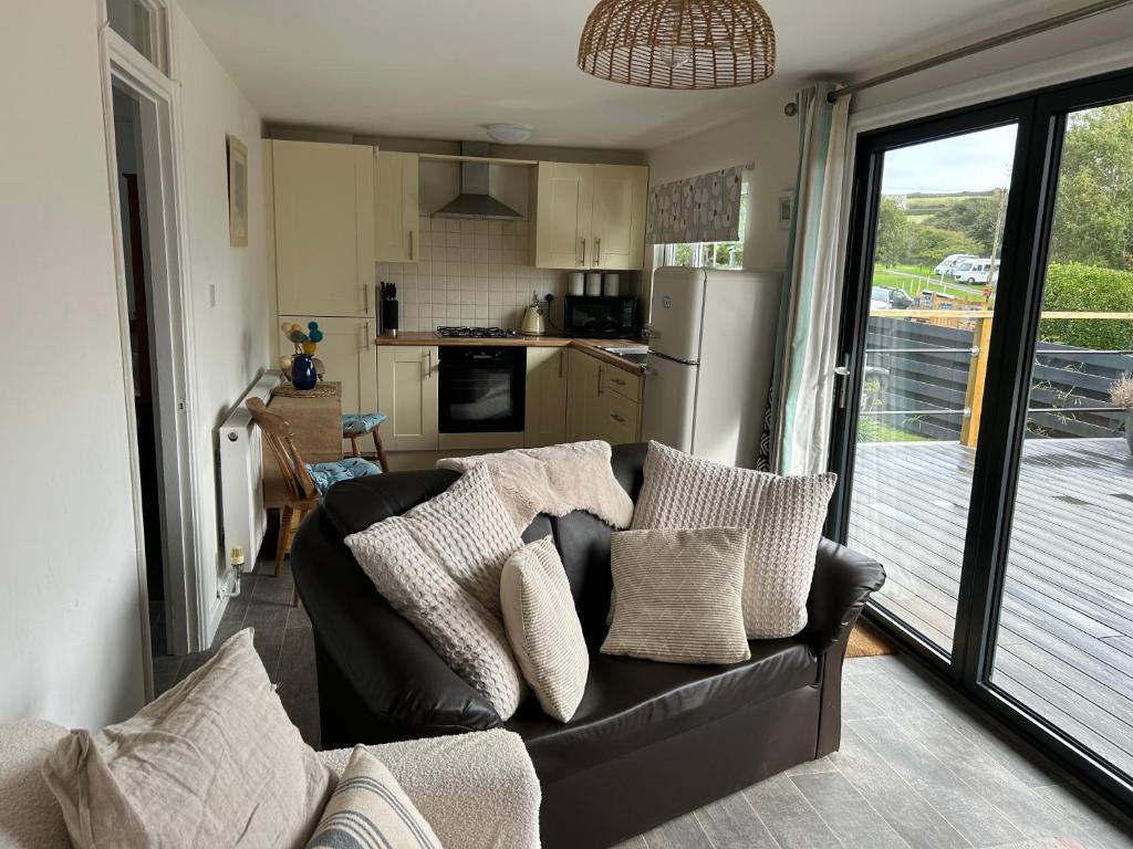 a living room with a couch and a kitchen at The Beach Hut in Perranporth