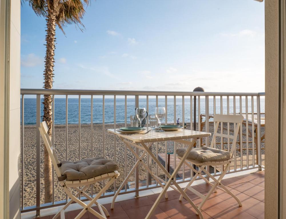 a table and chairs on a balcony with the ocean at Frente al mar y a pie de playa in Torrenueva