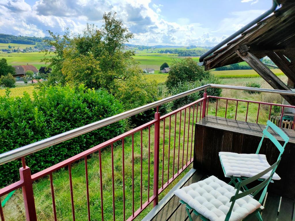 a balcony with two chairs and a view of a field at Ornithorynque in Noréaz