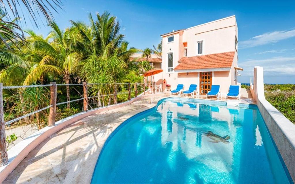 a swimming pool with blue chairs and a house at Casa del Mar in Akumal