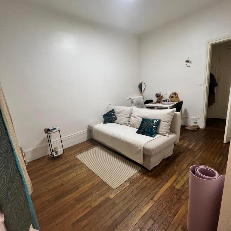 ein Wohnzimmer mit einem weißen Sofa und Holzböden in der Unterkunft 15 mins from Paris in La Garenne-Colombes