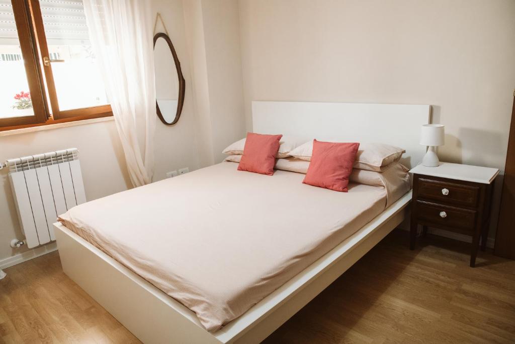 a white bed with two red pillows on it at as maison in Terni