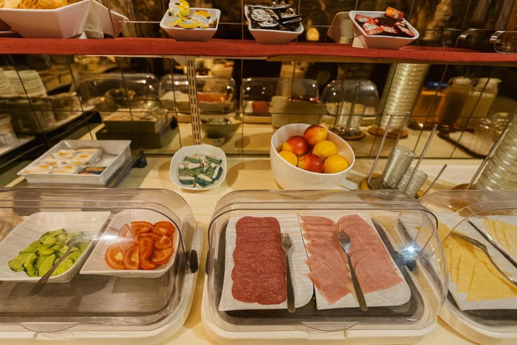 a buffet with meat and a bowl of fruits and vegetables at Atomis Hotel Düsseldorf City in Düsseldorf