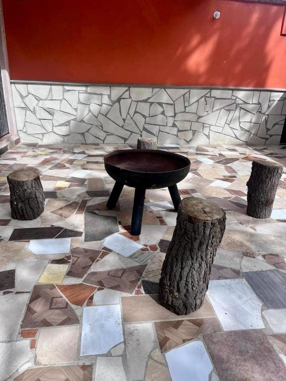 a table and two logs on a stone floor at Loft Industrial con fogatero in Mineral del Monte