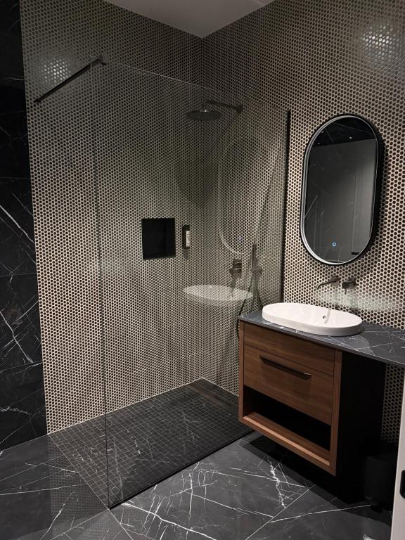 a bathroom with a shower with a sink and a mirror at Soho Boutique apartments in Ljubljana