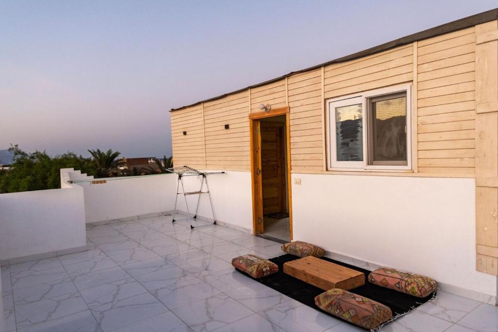 eine Terrasse mit einem Gebäude mit einem Fenster und einigen Bänken in der Unterkunft Sea and Mountain View Rooftop Chalet in Dahab