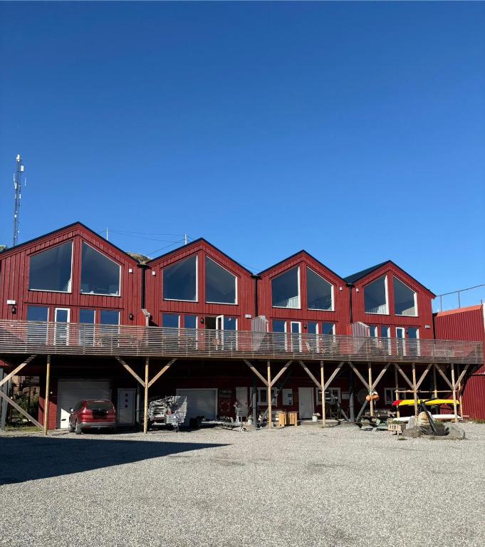 a large red building with a deck in a parking lot at Finnvika Panorama, Stamsund - Lofoten in Stamsund