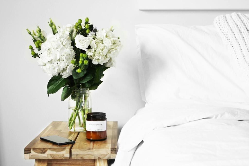 a vase of flowers on a table next to a bed at La Masia Costa Brava -Adults Only in Garrigás