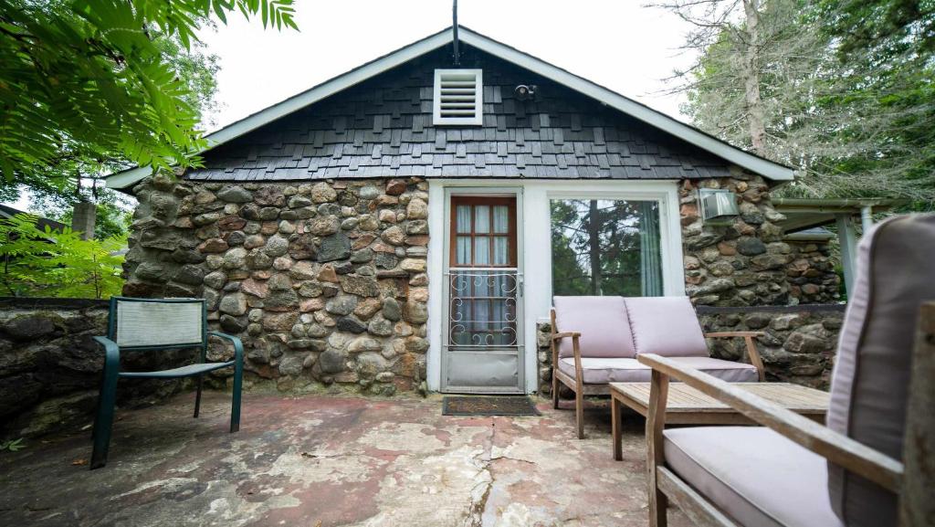 een klein stenen gebouw met een deur en stoelen bij 3-Bedroom Cottage #1 Hamilton in Sharbot Lake