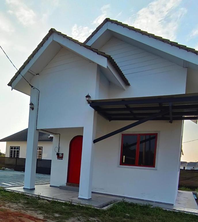 a large white house with a red door at De'5 Tiny House , Besut in Kampong Kubang Bemban