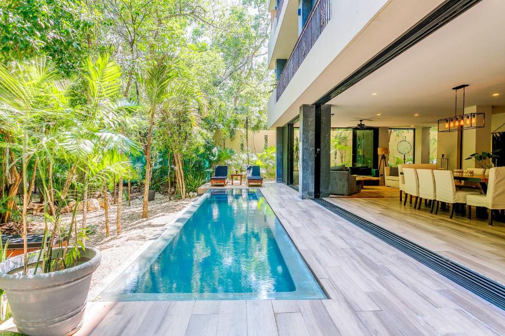 an infinity pool in a villa with a dining area and a house at Luxurious Oasis Jacuzzi with Art Gallery and Pool in Tulum