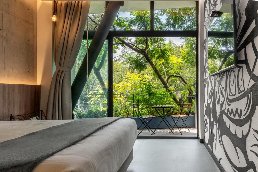 a bedroom with a bed and a large window at Street Art Hotel Roma in Mexico City
