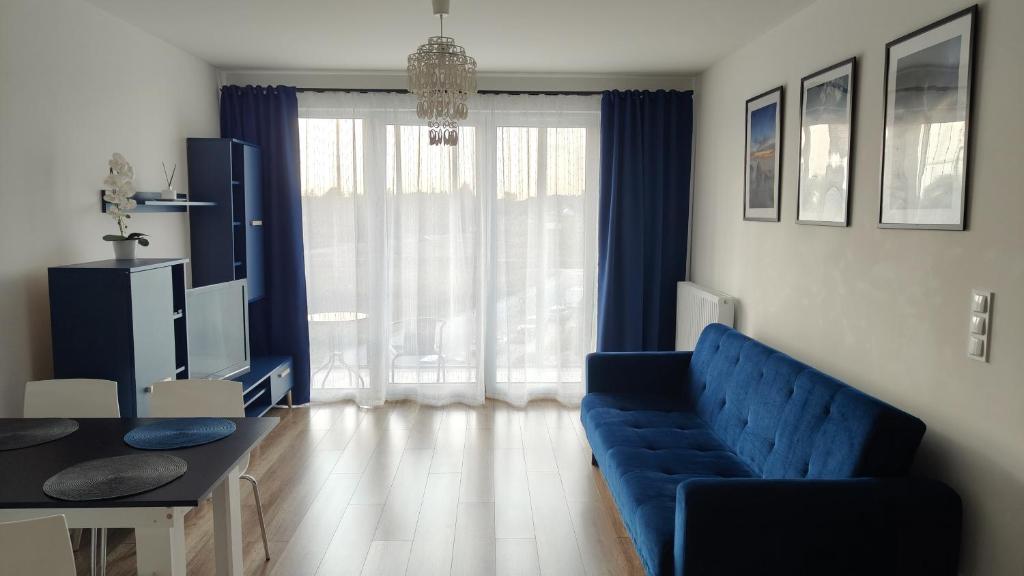 ein Wohnzimmer mit einem blauen Sofa und einem Tisch in der Unterkunft Apartament 24 Gdynia Zachód in Wiczlino