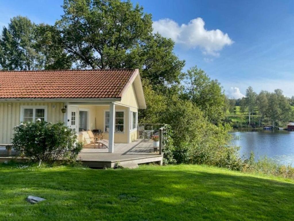 una pequeña casa con terraza junto a un lago en 4 person holiday home in BENGTSFORS-By Traum, en Bengtsfors