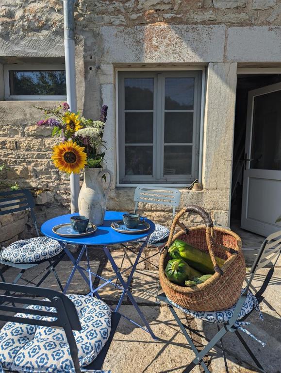 a table and chairs with a vase and a basket of vegetables at Bulle Nature in Publy