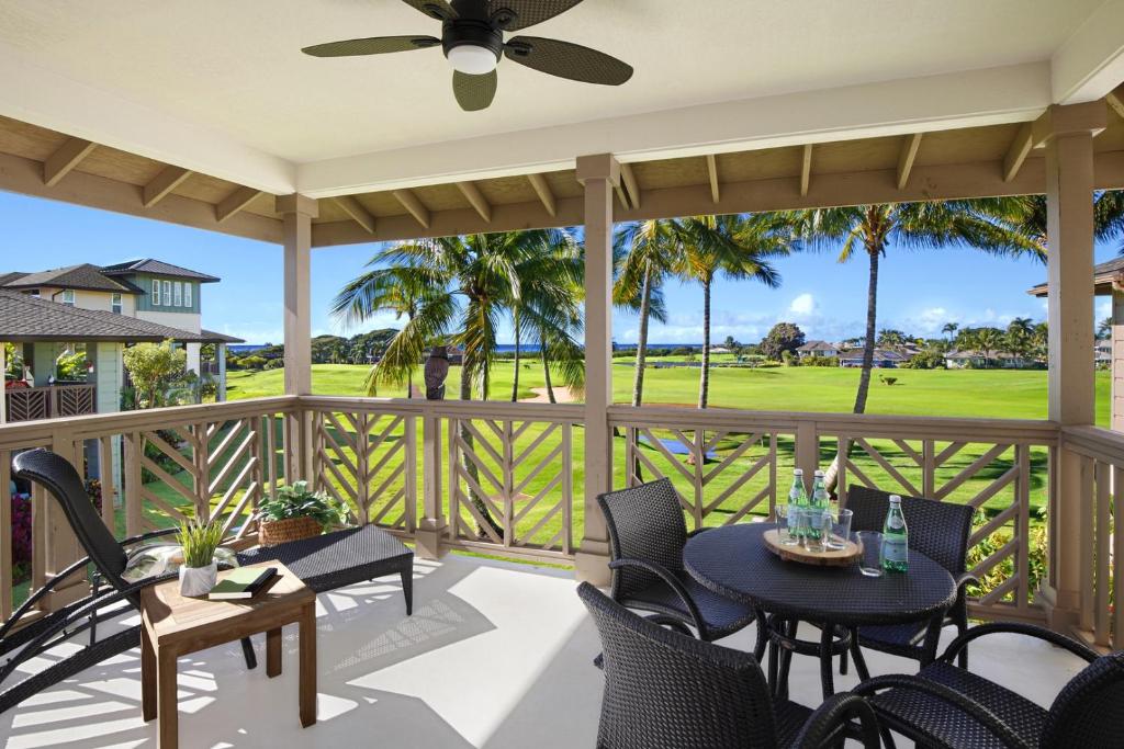 a porch with tables and chairs and a view of the golf course at Poipu Retreat with Golf Ocean Views and AC in Koloa