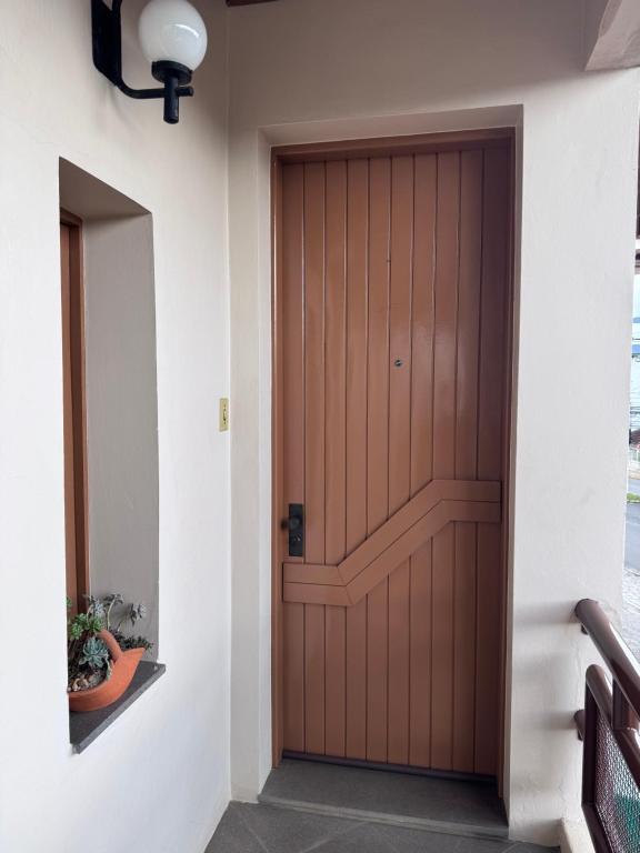 a wooden door in a hallway with a mirror at Apartamento espaçoso para locação - Bairro Universitário in Bento Gonçalves