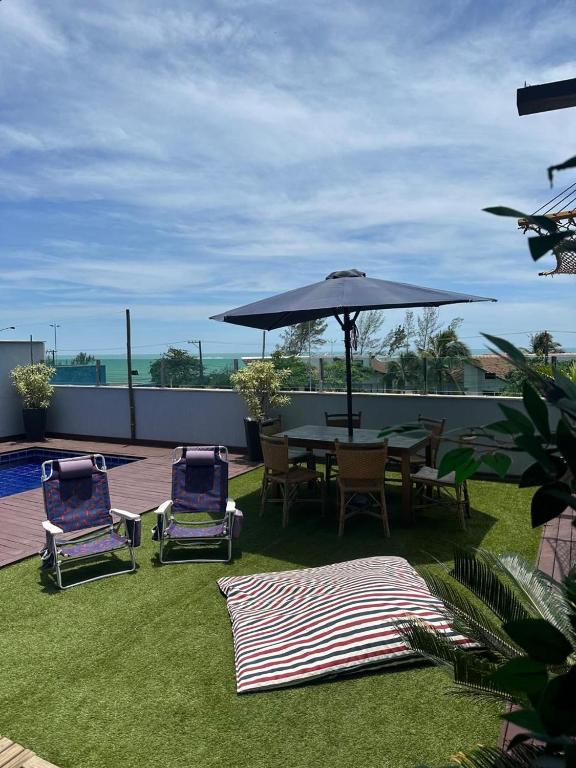 a patio with a table and chairs and an umbrella at Casa Da Enseada Azul com 5 SUITES - GUARAPARI in Guarapari