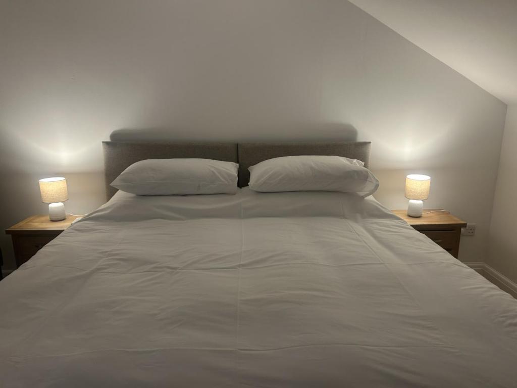 a white bed with two lamps on two tables at Richmond, Keswick town centre apartment in Keswick