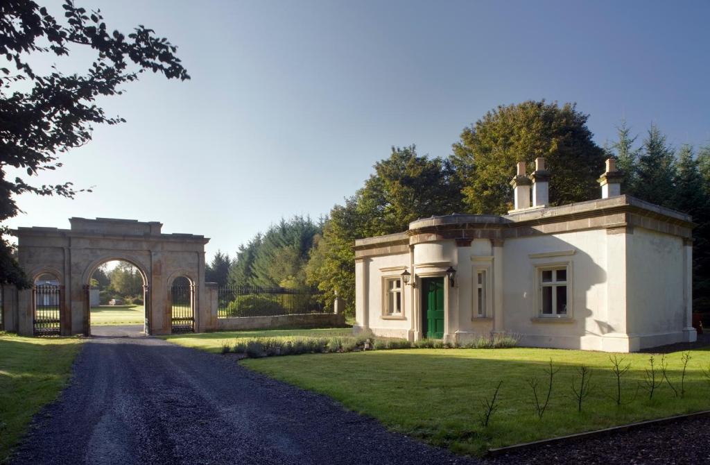 une grande maison blanche avec un portail et une allée. dans l'établissement Triumphal Arch Lodge, à Creagh