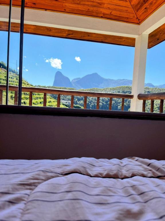 a bed in a room with a large window at Pedra Azul - Casa Goiabeira II in Domingos Martins