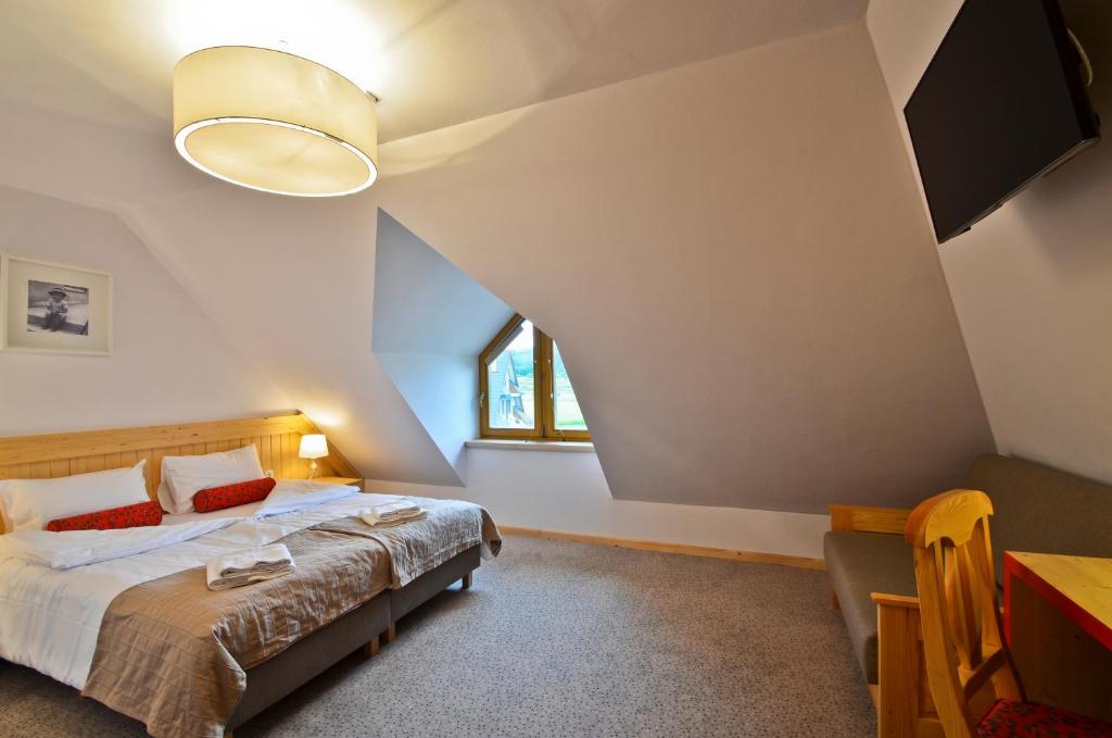 um quarto com uma cama, uma mesa e uma janela em Spiski Dworek em Jurgów