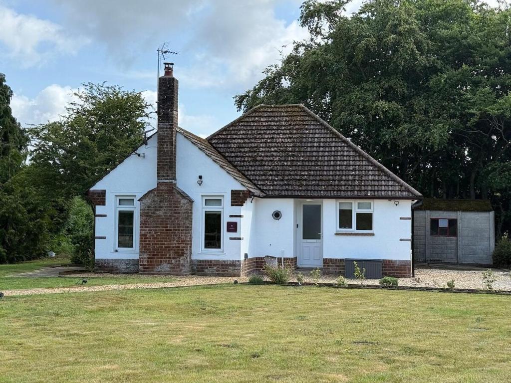 a small white house with a chimney on a yard at Pendene in Hinton