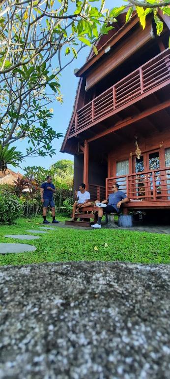 a group of people sitting on a bench in front of a building at Umah Lumbung Estetik in Tanah Lot