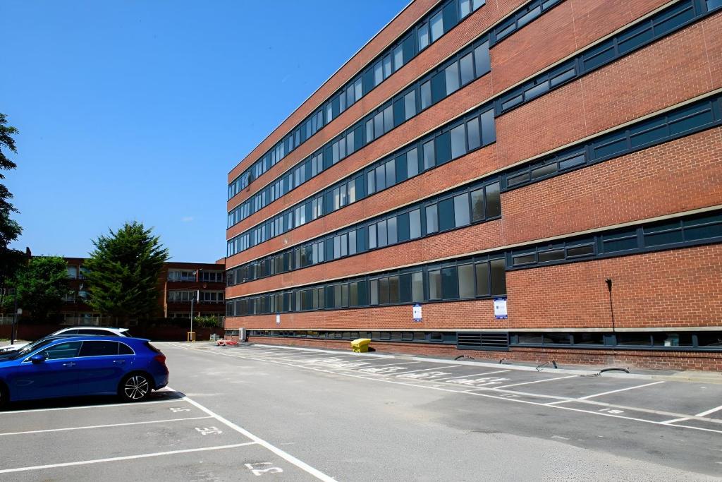 a blue car parked in a parking lot in front of a building at Luxuriously Cosy 1 Bed Flat at Trinity Point Gravesend, Suitable for Long Stay and Short Stay in Gravesend