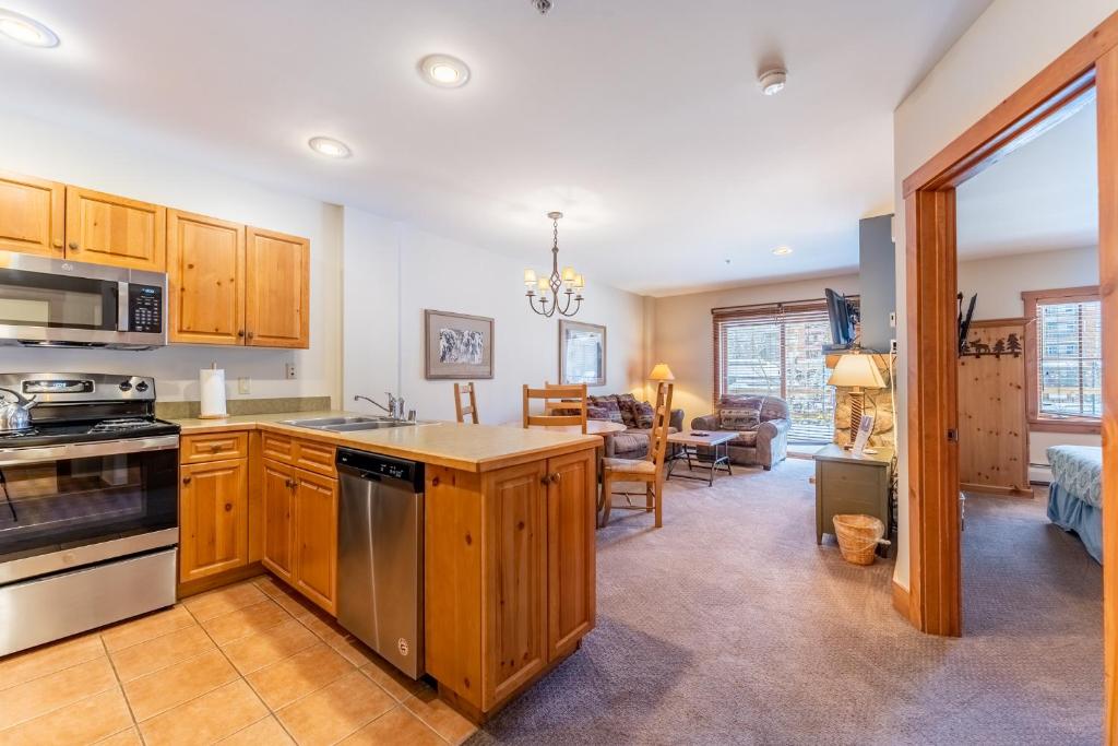 a kitchen with wooden cabinets and a living room at Expedition Station 8581 by Summit County Mountain Retreats in Snake River Health Services Incorporated Heliport