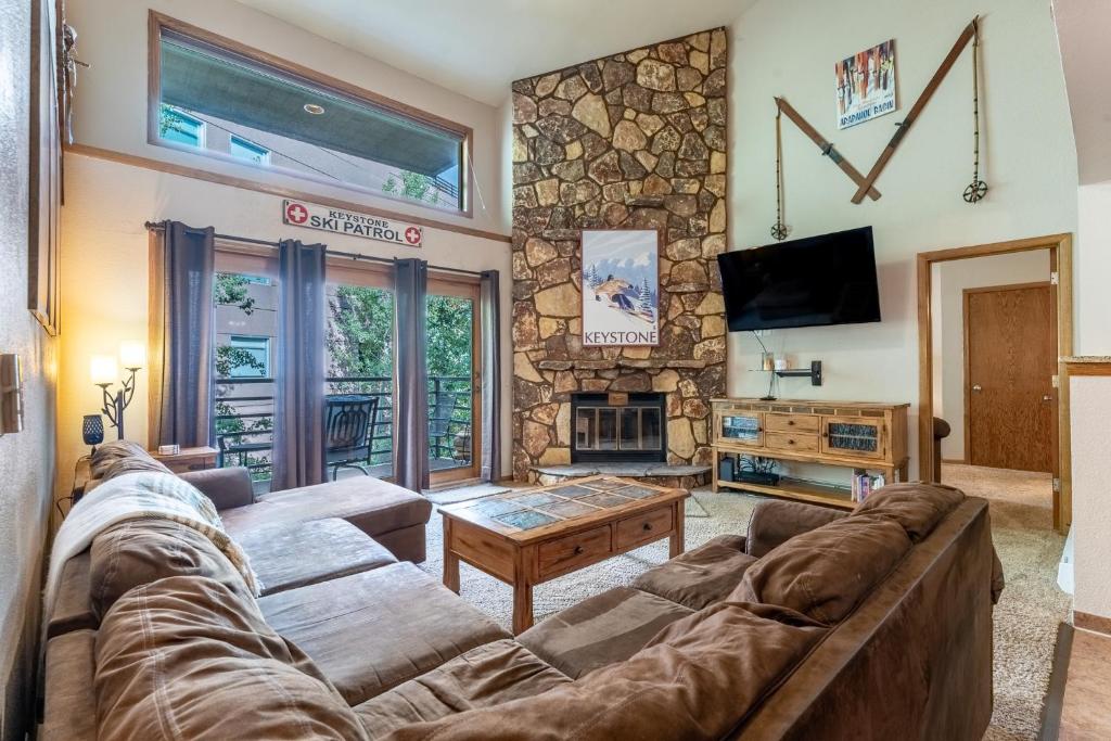 a living room with a couch and a stone fireplace at Snowdance Manor #405 : 2 in Keystone