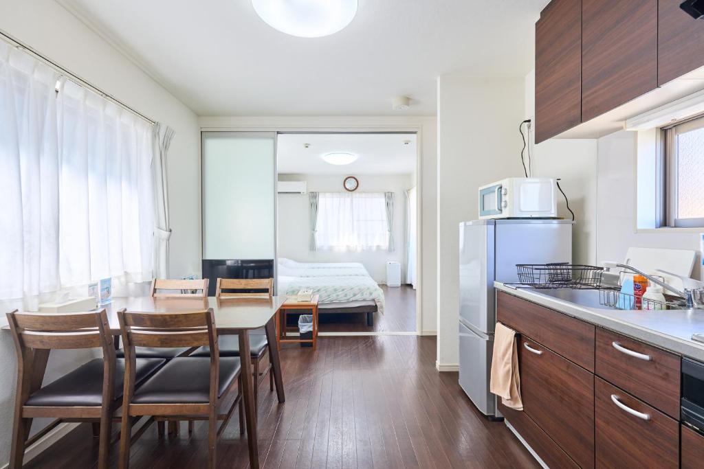 a kitchen and dining room with a table and a room with a bed at KOSHIGOE seaside inn in Kamakura