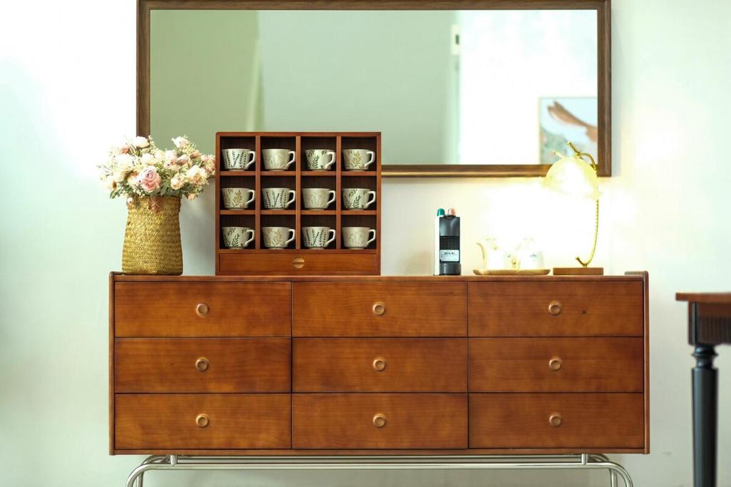 a dresser with a mirror and a vase of flowers on it at Comfy Sofy-Bunny Vintage Penthouse in Tanah Rata