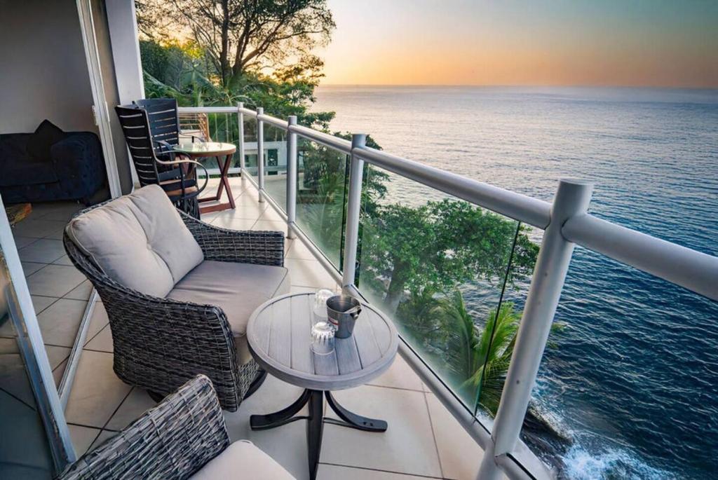 a balcony with chairs and a table and the ocean at Oceanfront 4BR 20 PAX in Puerto Vallarta